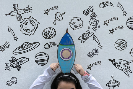The girl is taking a rocket painting on her head. Interested in science, Painting Stars, bubbles, spacecraft. the solar system, the search for truth. STEM Education concept.の写真素材