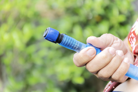 Close up of old female diabetes patient making subcutaneous insulin injection into her abdomen with insulin pen syringe at home. Diabetes, health care and medical concept. Diabetes World Day.の写真素材