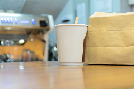 Coffee and bread, Donut, breakfast is popular. Coffee paper and brown paper bags are the packaging placed on the counter shop. The background is the coffee shop is open.の写真素材