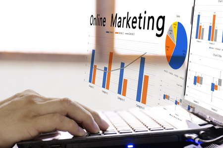 Online marketing concept. man who is planning a sale of online marketing. To increase sales more and more. Focus hand working on laptop. Graphs generated by the program.の写真素材