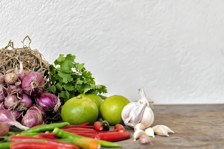 Seasoning concept. Composition of various herbs and spices isolated put on a wooden table. Shallots, garlic, chili, coriander, lemon. Space to enter text. DoF focus.の写真素材