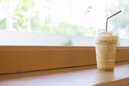 Blended coffee is popular in Asia, Packed in plastic glass. Is a refreshing and cool drink placed on a wooden table.の写真素材