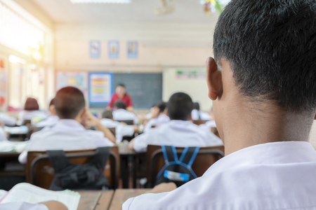 Education concept. the classroom environment in which the students are intending to study seriously. The front scene is a student, the background as a teacher is teaching.の写真素材