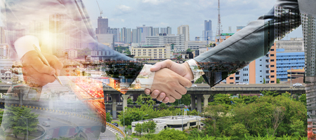 Business man signing contract making a deal and Shake hands to invest concept. Agreement was signed co-investment business, Panorama.âª Double Exposure.The background is the city atmosphere.の写真素材