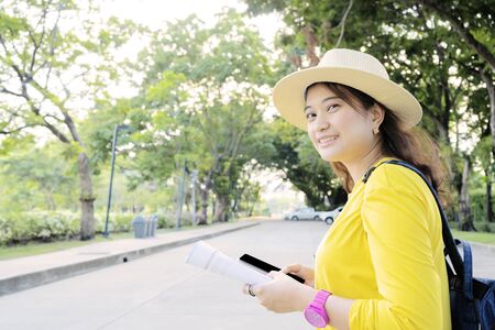 Women tourists are using smartphones to search for tourist information. In the hand are holding detailed books about interesting attractions.の写真素材