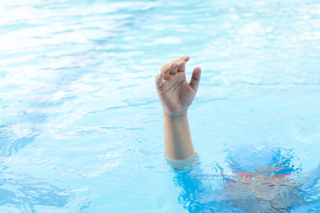 Children are drowning in danger, needing help. Not a parent taking care of swimming until an accident. Hands that are held on the surface of the waterの写真素材