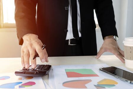 Businessmen are calculating with calculators to calculate costs and profits. Good marketing planning must be prudent. With analysis from graph statistics.の写真素材