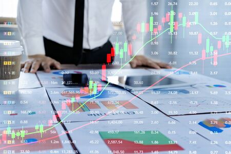 Businessmen are planning to invest in the stock market. By documenting the analysis table to be placed on the desk to check for disadvantages, solutions, Red-green line graphics.の写真素材