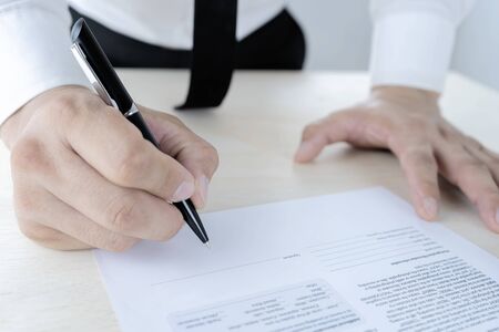 Businessmen are signing contracts. Wearing a white shirt Black slacks, black tie, dignified look, Complete business agreement with signatures.の写真素材