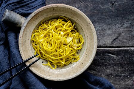 Stir-fried noodles with cabbage in a bowl, placed on a wooden table. Popular Asian food Made from wheat flourの写真素材