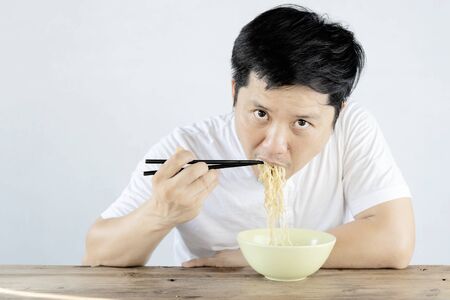 Asian men are eating instant noodles with deliciousness. Is a popular food Both delicious and cheap But lack of nutrients the body needs.の写真素材