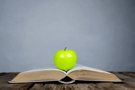 Back to school concept, for educational success. Books placed on the table and on top are green apple. The background is an empty blackboard that can be put on advertising media.の写真素材