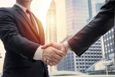 Business concept. deal, joint venture, start up. Businessmen handshaking, on city building background, employment and hiring, enterprisers making good business deal after successful negotiations.の写真素材