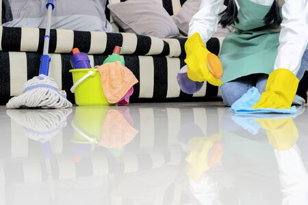 Housekeeper wiping the floor with cloth, And she used to wipe the spray to help. Wear rubber gloves to protect chemicals.の写真素材