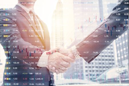 Investment in the stock market concept. deal, joint venture, start up. Businessmen handshaking, on city building background, Image of stock market trading numbersの写真素材