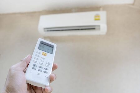 The hand that is holding the remote to control the air conditioner requires a cooler temperature....