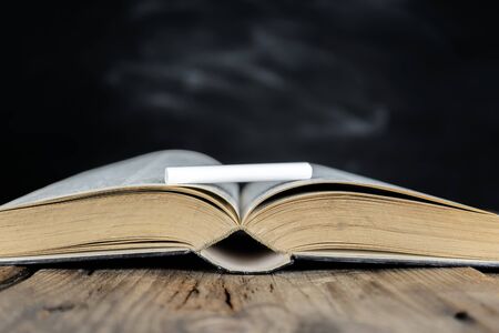 Back to school concept, for educational success. Books placed on the table and on top are chalk. The background is an empty blackboard that can be put on advertising media.の写真素材