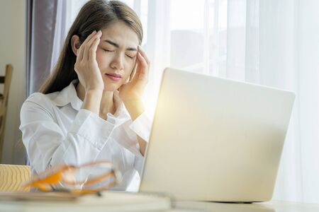 Portrait of a young tired businesswoman using laptop and working on some reports from home. focused...