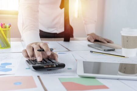 Business is about the use of financial calculators. Tax, financial, revenue, expenses, income, earnings, financial investments, stocks, The graph document is arranged on the table.の写真素材