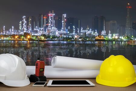control concept. Oil refinery capacity to produce energy, the front desks of the engineers, with helmet, Tablet, radio, schematic drawings placed.の写真素材