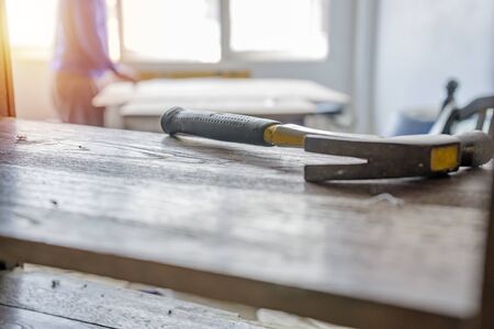 Carpenter building a house and workimg with hammer and wood. The hammer is a front scene object.の写真素材