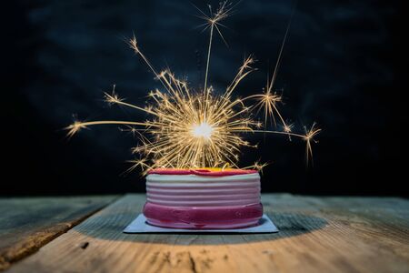 Celebrating success concept with beautiful colored cakes, fireworks that are spreading light. Placed on the dining table.の写真素材