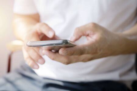 Holiday of business people are using smart phones to monitor the work.  typing text message at social network using cell phone, sitting on sofa at home, Close up of a man using mobile smart phone.の写真素材