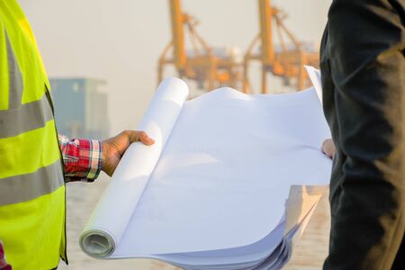 Consult about project plans, work on large industrial projects. Engineers and experts are reviewing the workflow, Holding a blueprint.の写真素材