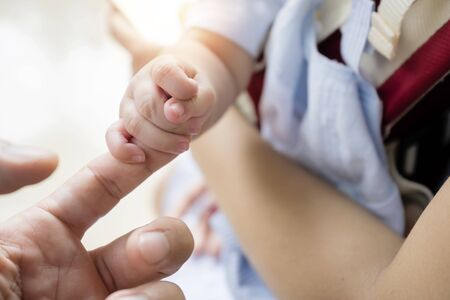 Family relationship concept. The baby is holding his father's fingers, with the baby in her mother's bosom.の写真素材