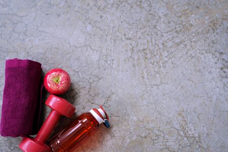 Flat lay composition with, healthy food and sport equipment on cement floor background. Exercise is essential and important, towel, bottle of water, apple red, Dumbbell.の写真素材