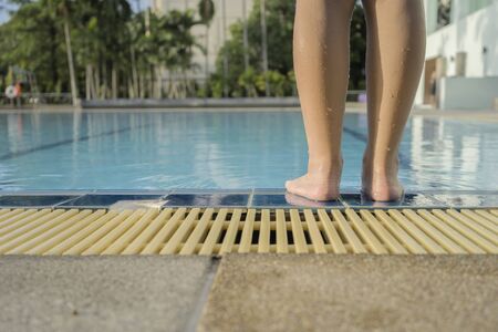 child who have to use a lot of courage in swimming. needs courage to decide to jump into the pool, Standing by the pool. Prepare yourself to prepare concept.の写真素材