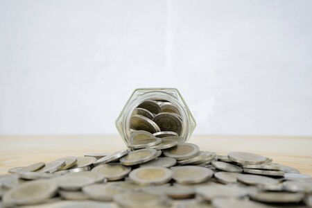 Saving for the future concept. A glass piggy bank with coins piled a lot on the table. Planning, investment funds, financial income from dividends, interest increased.の写真素材