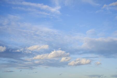 The sky is full of clouds floating around, both small and large, the sun is shining brightly.の写真素材