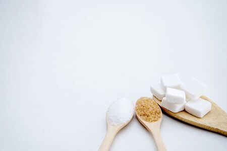 White sugar, brown sugar, sugar cubes, placed in a wooden spoon, white background. food conceptの写真素材