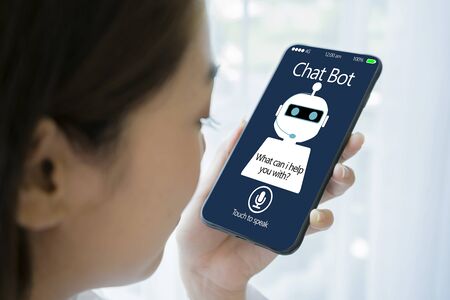 artificial intelligence,AI chat bot concept. Hands holding mobile phone on blurred abstract background. chatbot answering questions online, robot assistant help on websiteの写真素材