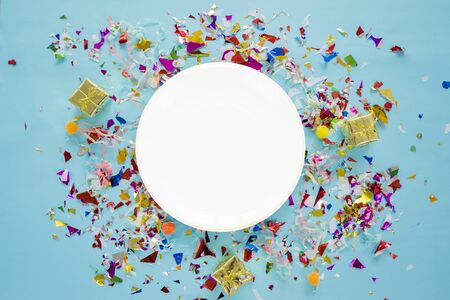 Celebrate success concept. A white circular dish placed in the middle, colorful scraps of cellophane and a golden gift box. The festival party appreciated success.の写真素材