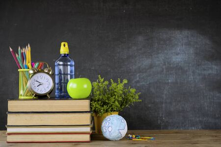 Education concept - books on the desk in the auditorium. School books on desk or back to school on black backgroundの写真素材