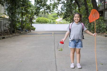 Cute Asian Girls are learning from her adventure with nature, set out to catch insects with sticks containing insect net and cans. Education, Self-learning experience. She is committed concept.の写真素材