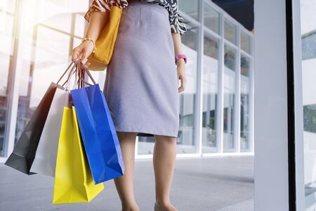 Shopping concept. A woman standing carrying a colorful paper bag obtained from shopping. She is happily traveling back to buy the things she needs.の写真素材