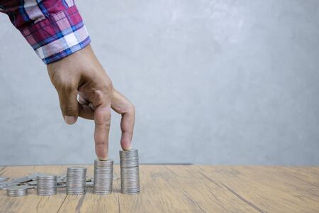 Systematic financial investments concept, and continuous gains, compared to stair steps. Business people use their fingers to walk up a pile of coins.の写真素材