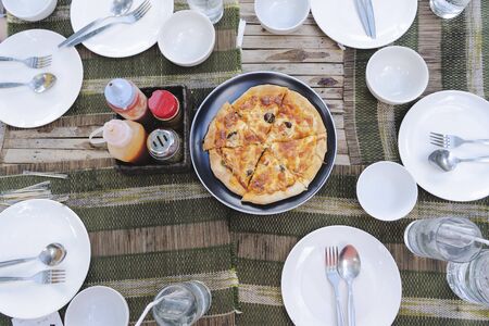 Lunch concept, dinner table with many white dishes, along with pizza trays. 6 pieces of pizza, Sauces and spices are placed as an element.の写真素材