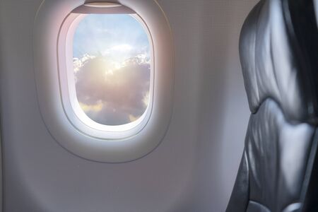 Window View From Passenger Seat On Commercial Airplane. Beautiful view from the window of airplane to blue sky with white clouds sunshine at height in sunny day from the passenger seat.の写真素材