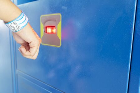 An Asian woman is scanning the barcode to open the locker. Paper wristbands are tough, durable.