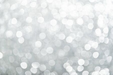 A brilliant blurry white background for a festive mood. Template for greeting card for entertainment. white abstract background bokeh blurred beautiful shiny lights Christmas.の写真素材