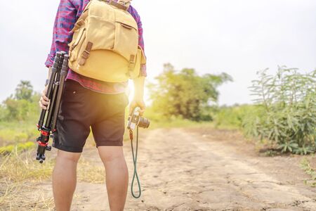 Asian photographers carry a camera bag along with a camera and tripod. Standing in the midst of...