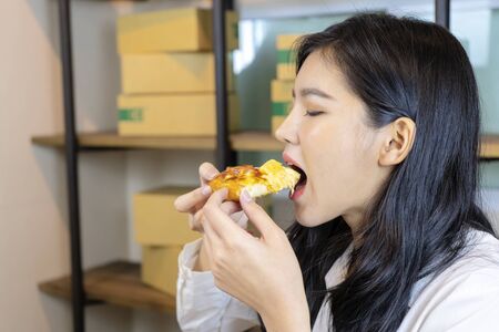 Cute Asian woman eating delicious pizza, she is not afraid of obesity, happy to eat.の写真素材