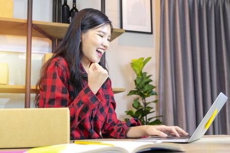 Online selling concept, cute Asian woman. She successfully closed the sale. She works at her home, where she is free to work.の写真素材
