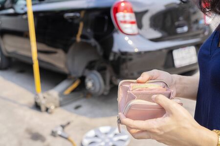 Pay for car repairs, cars that are being repaired in the center. Select the focus, The front scene is the hand that is opening the wallet.の写真素材