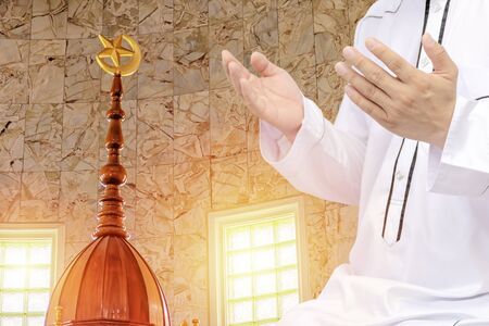Religious muslim man praying inside the mosque,Men are praying their God Of Islam,Put the pure white dress the two sides to the mouth. Faith in Islamic. Crescent moon at a top. Light of hopeの写真素材