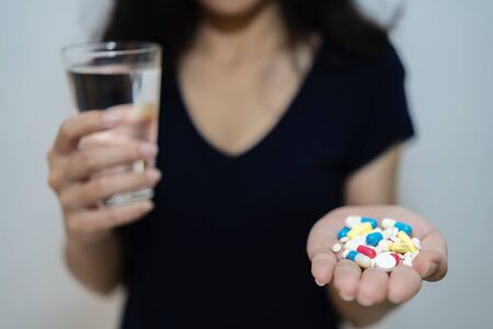 An Asian woman, she is sick, is about to take medicine to treat the illness. One hand was put on...